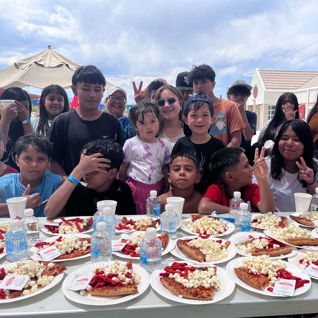 A group of latino students posing for a picture in front of a table covered in slices of pie on plates.