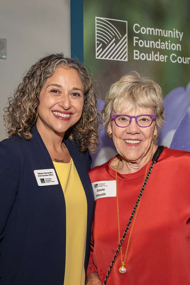 Two women pose for a photo in front of a Community Foundation Boulder County banner